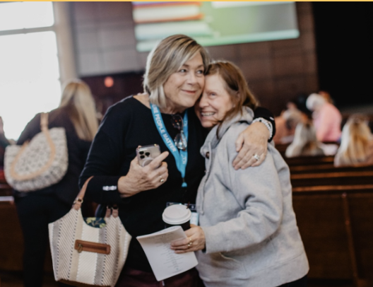 Two women hug after a womens ministry event.