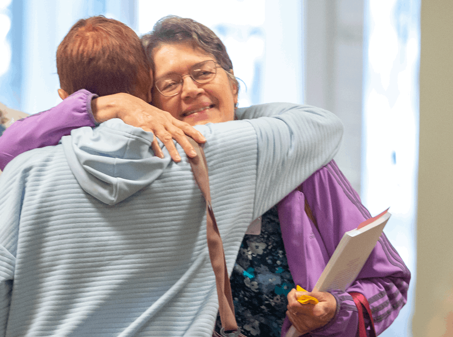 Two women embrace after life groups at church.