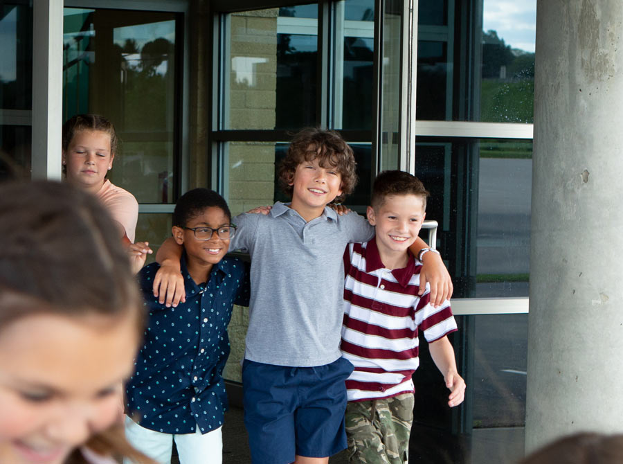 A group of happy boys leaves church with arms around each other.